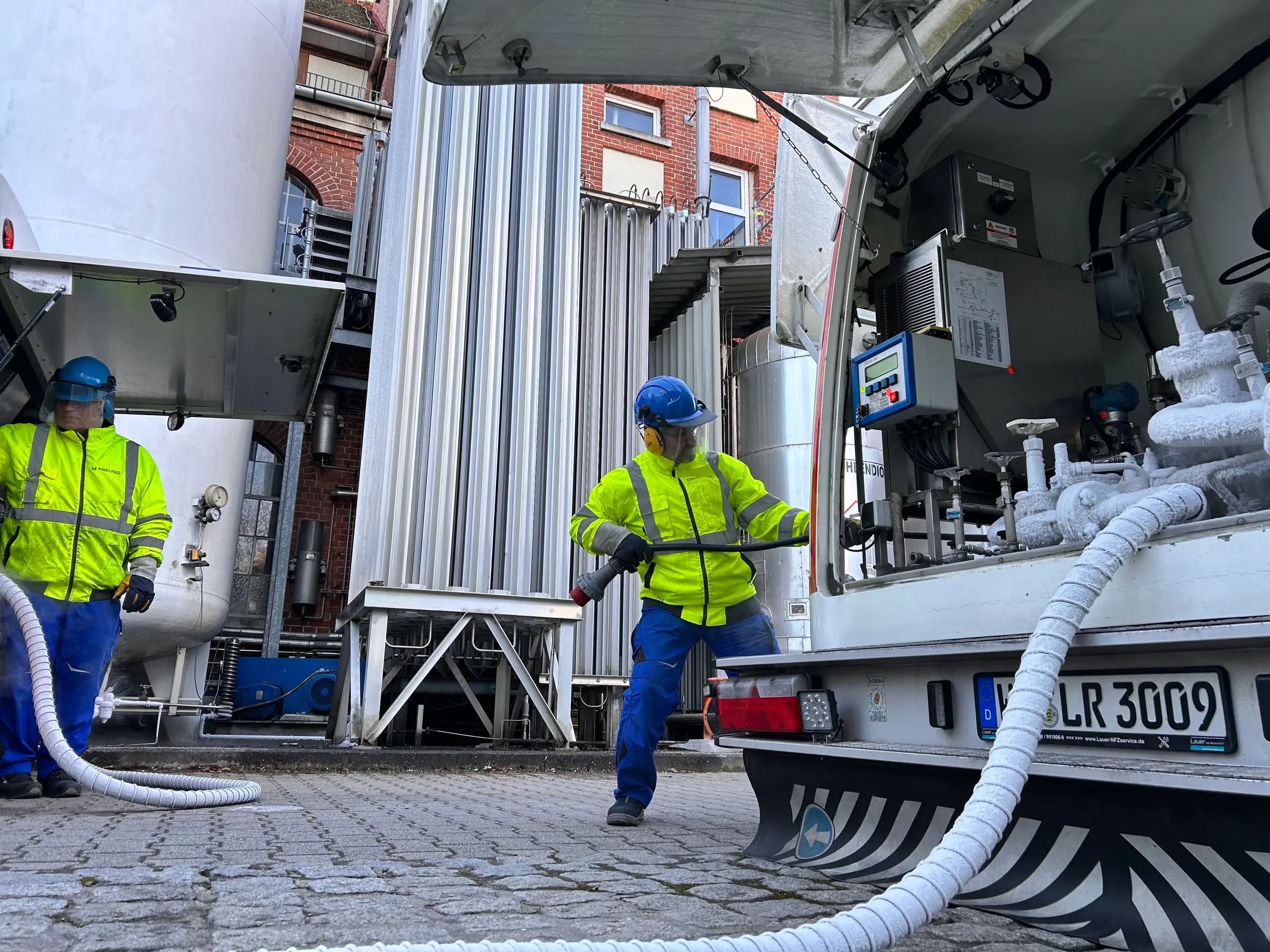 Zwei Mitarbeiter beim Umfüllen von tiefkalt verflüssigtem Gas am Bedienstand des Tankwagens
